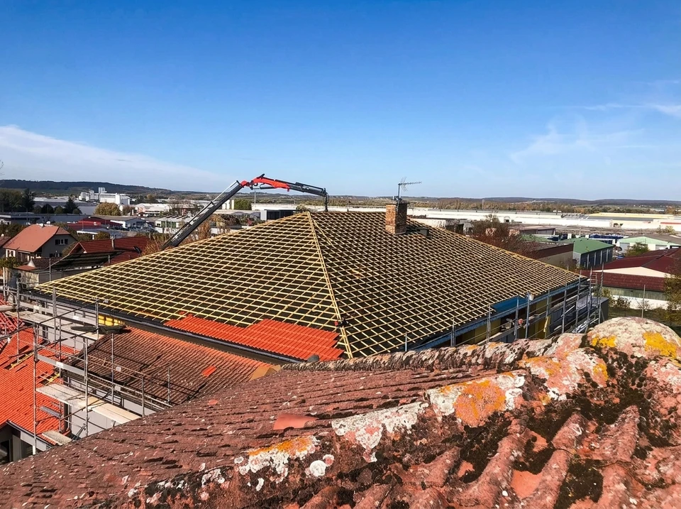 Toiture méditerranéenne avec tuiles canal en terre cuite rouge-orangé disposées en rangées régulières sous un ciel bleu nuageux