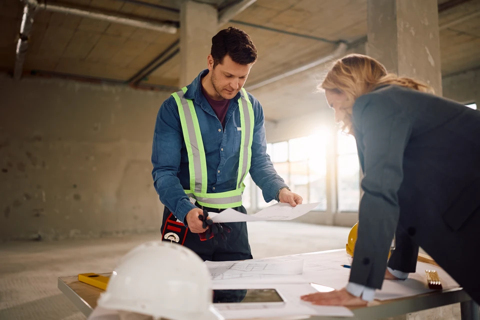 Ingénieur de structure et architecte et contremaître travailleur avec des plans discutent, abonnement travaillant pour le chantier de construction en plein air